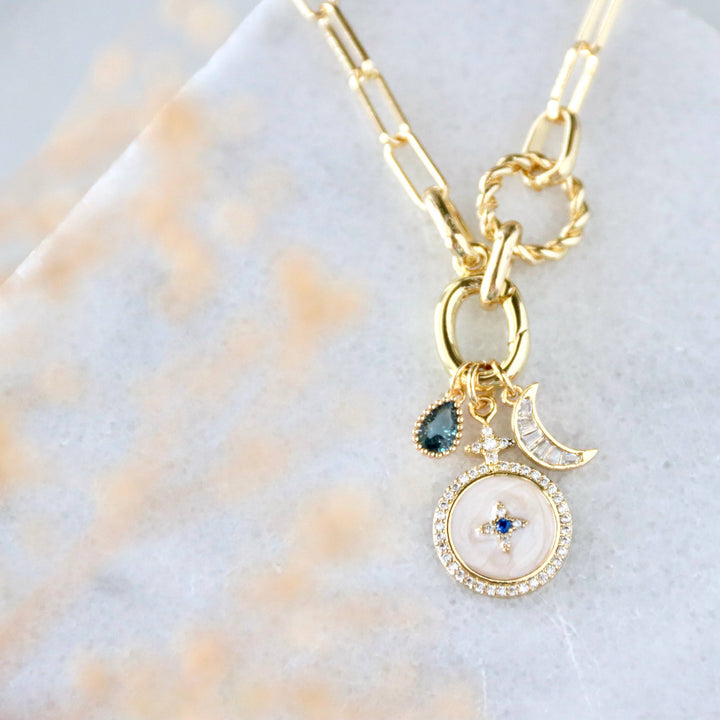 Gold necklace with charms on a light background