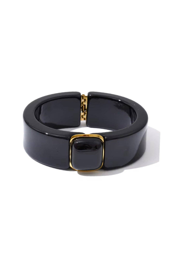 Black bracelet with gold accents on a white background