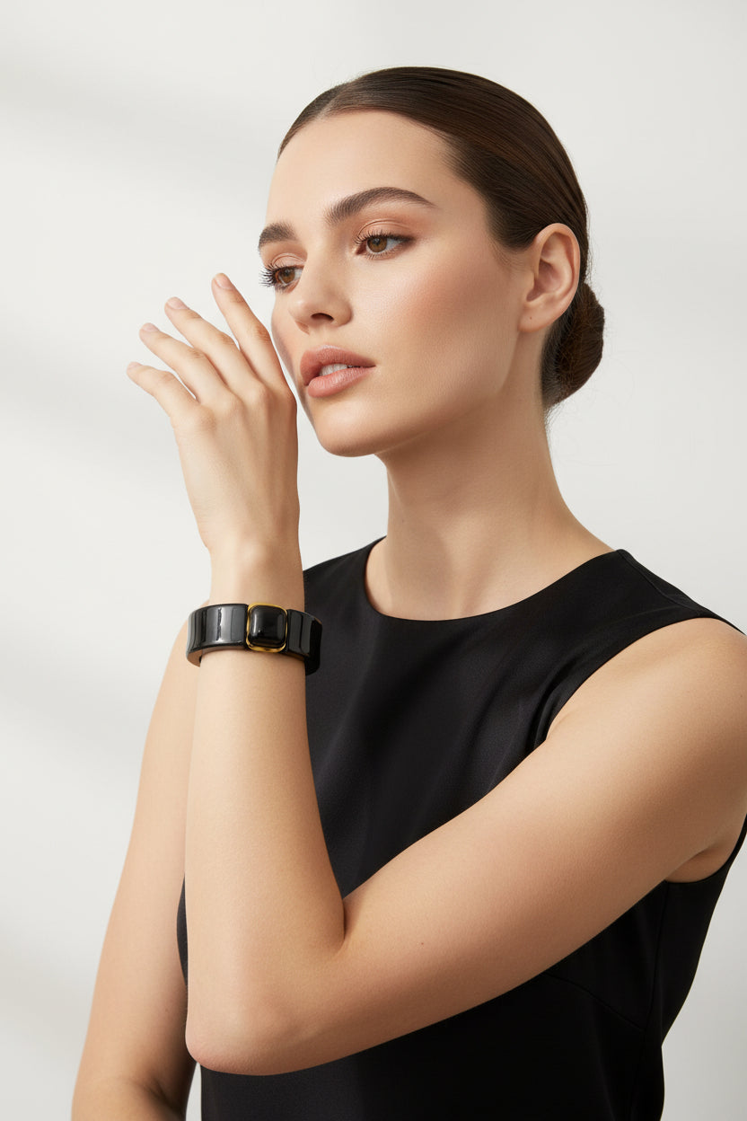 Black bangle bracelet with gold accents on a white background