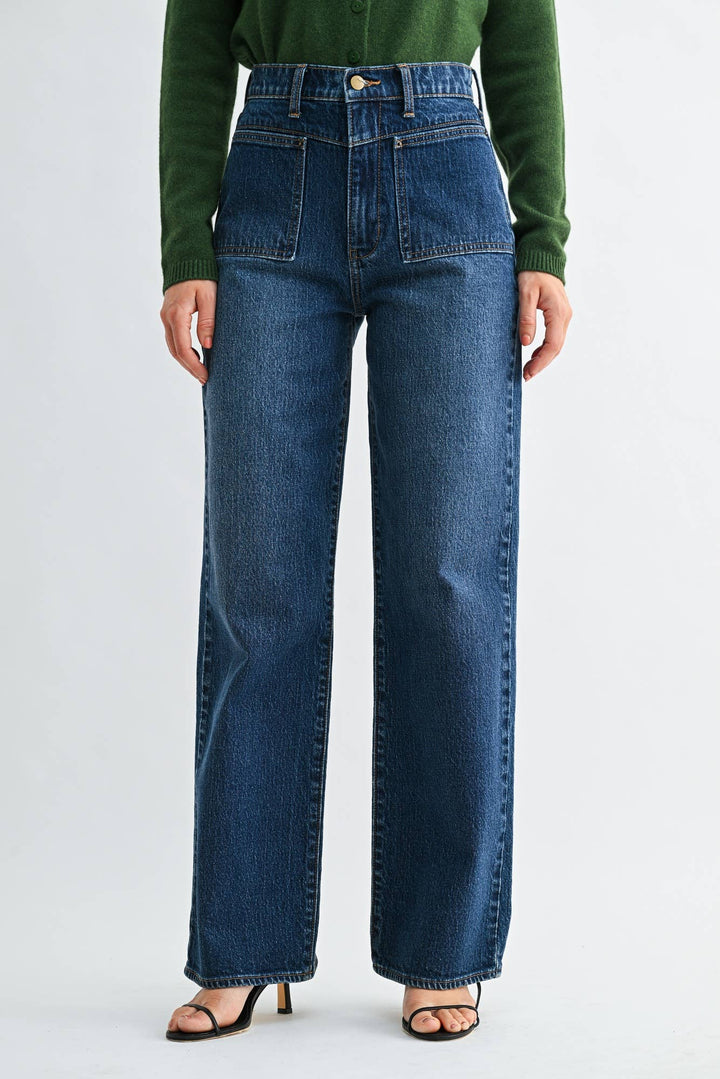 Woman wearing dark wash wide leg jeans with patch pocket detail on a plain background