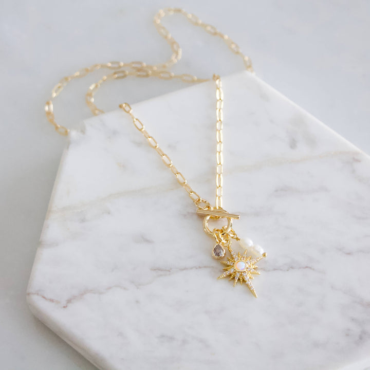 Gold necklace with a star pendant on a marble surface