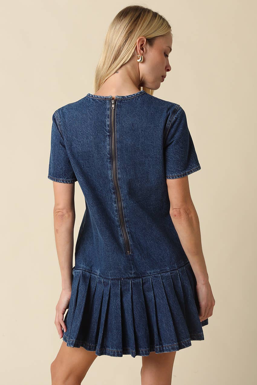 Woman wearing a blue denim mini dress against a beige background