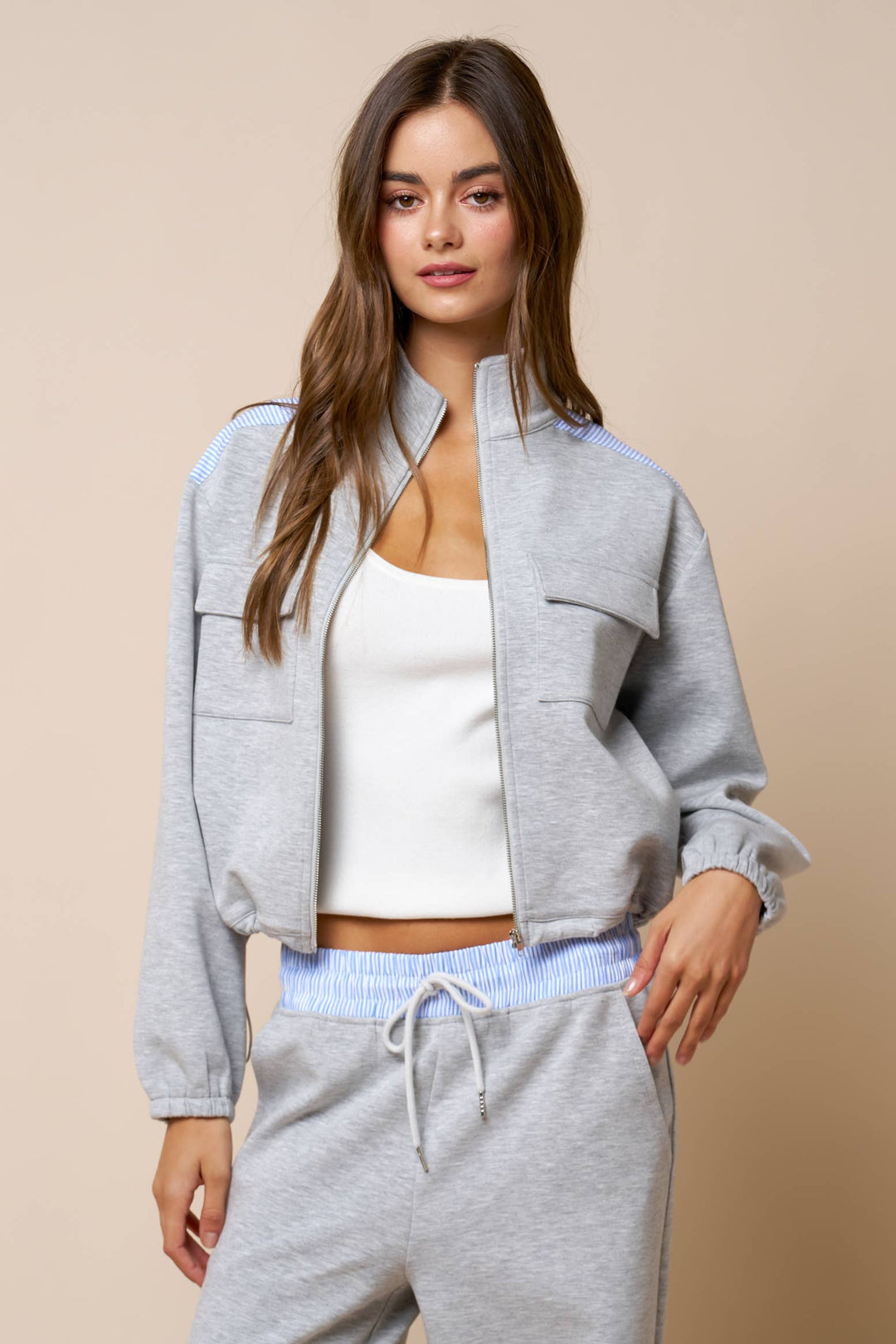 Woman wearing a gray tracksuit with a beige background