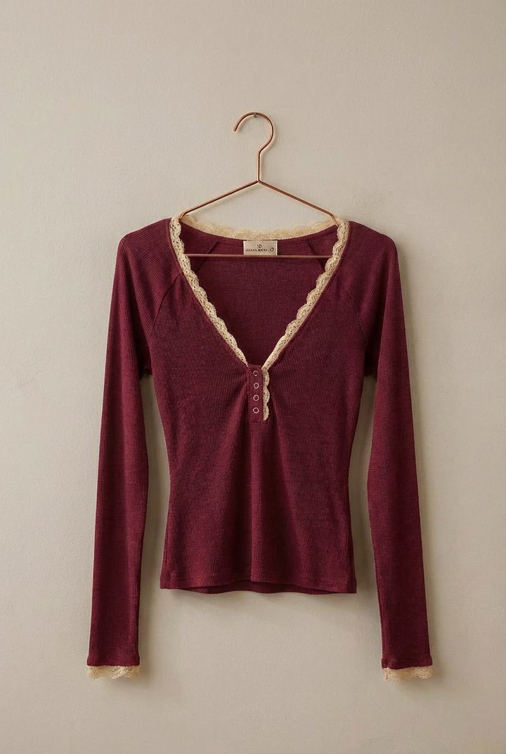 Maroon long-sleeve top with lace trim on a hanger against a beige wall