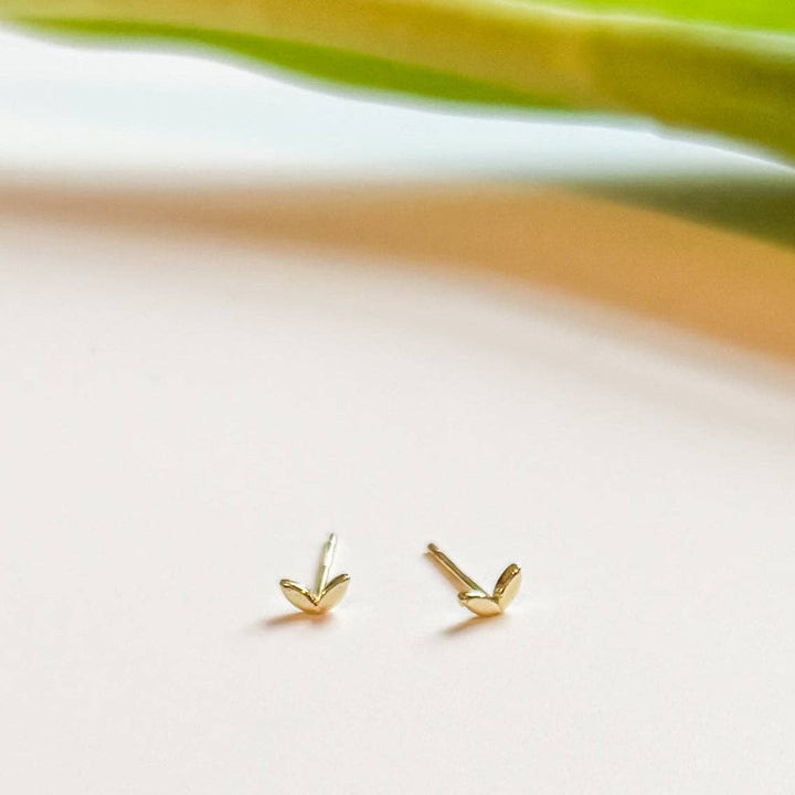 Gold heart-shaped stud earrings on a light background.