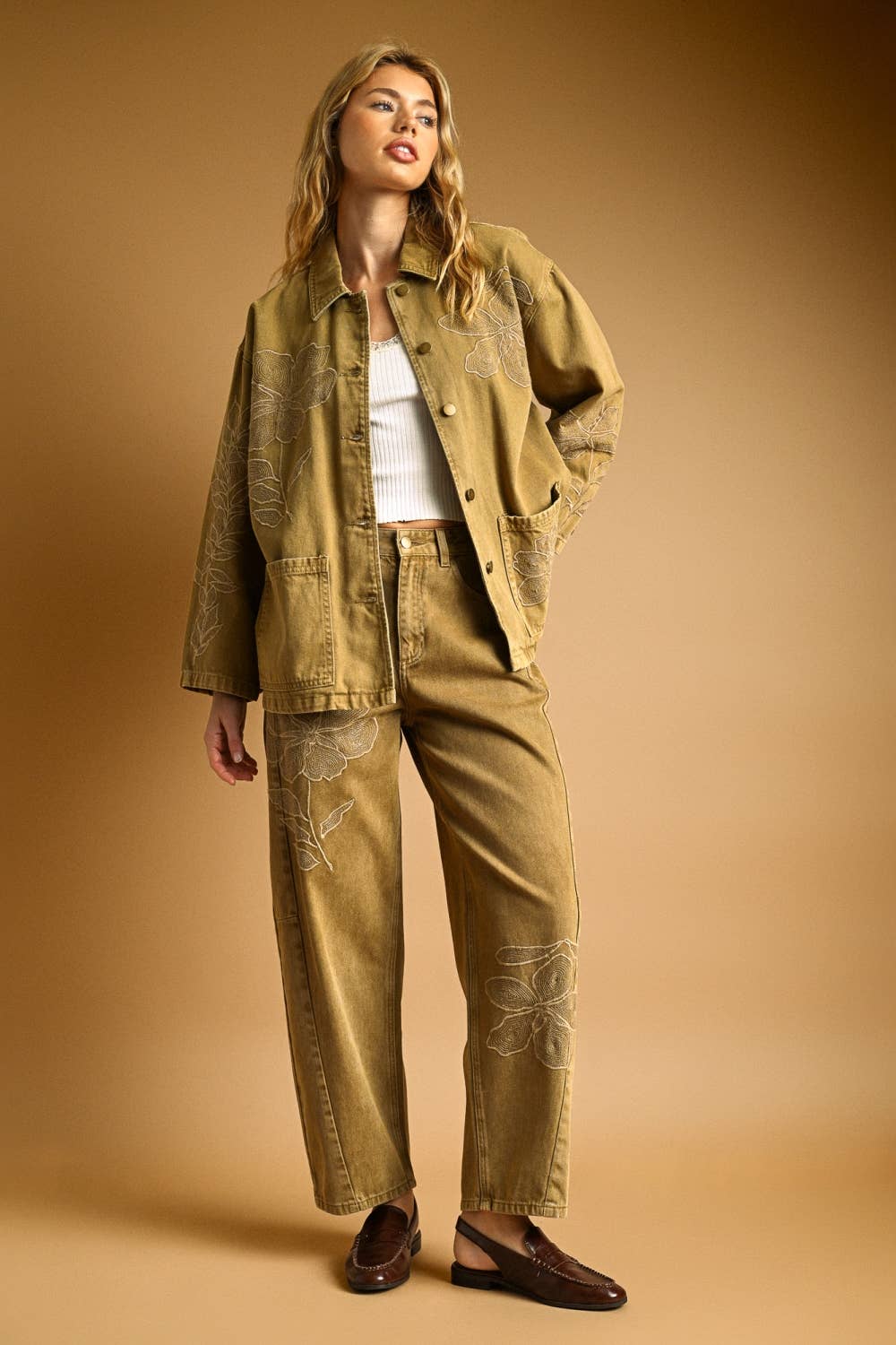 Woman wearing a beige jacket and embroidered barrel pants on a beige background