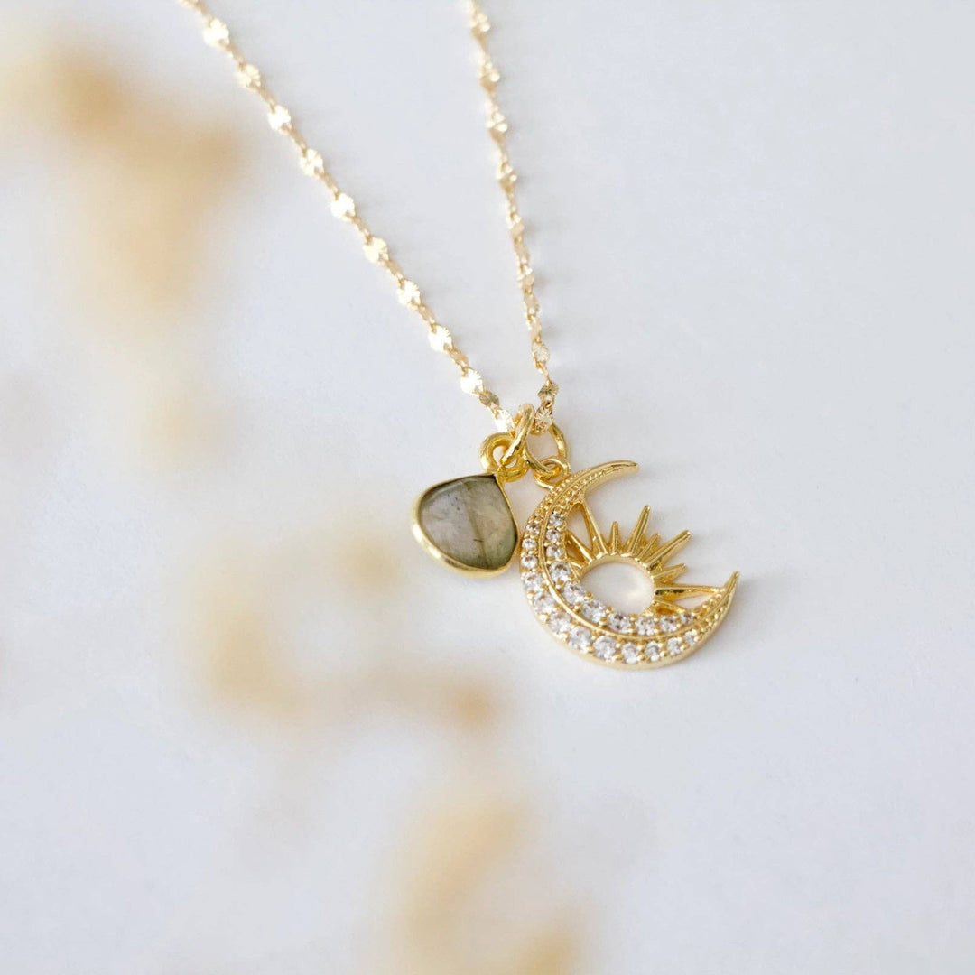 Gold necklace with moon and sun pendant with labradorite gemstone and CZ on a light background