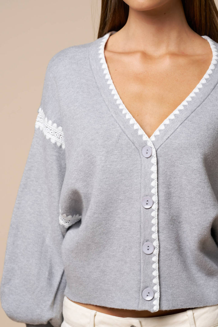 Gray cardigan with white trim and buttons on a beige background