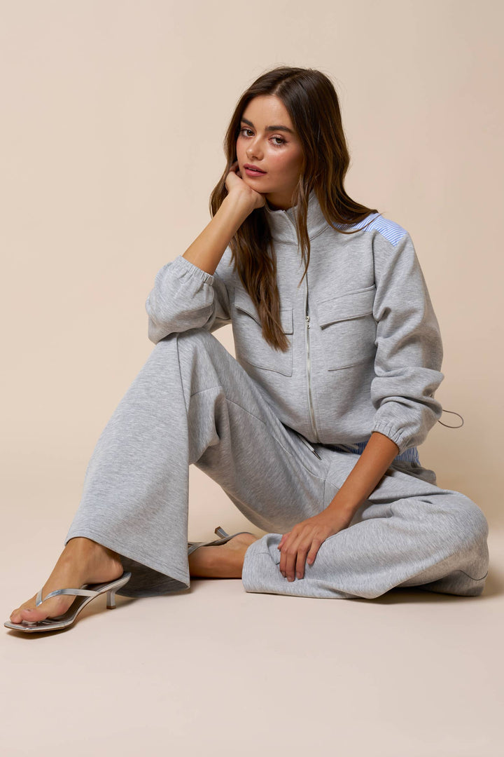 Woman wearing a gray tracksuit sitting on a beige background