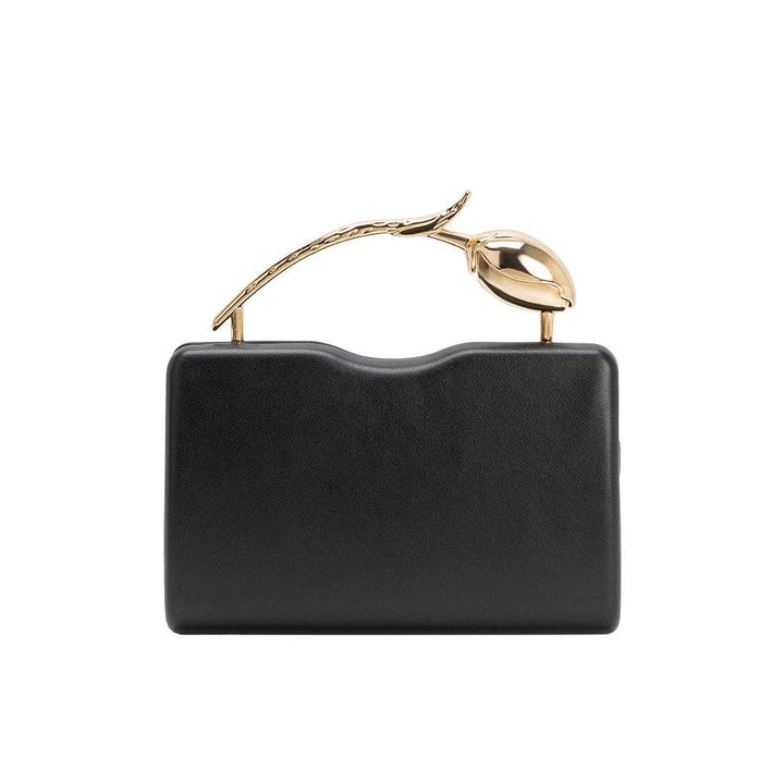 Black handbag with a gold handle on a white background