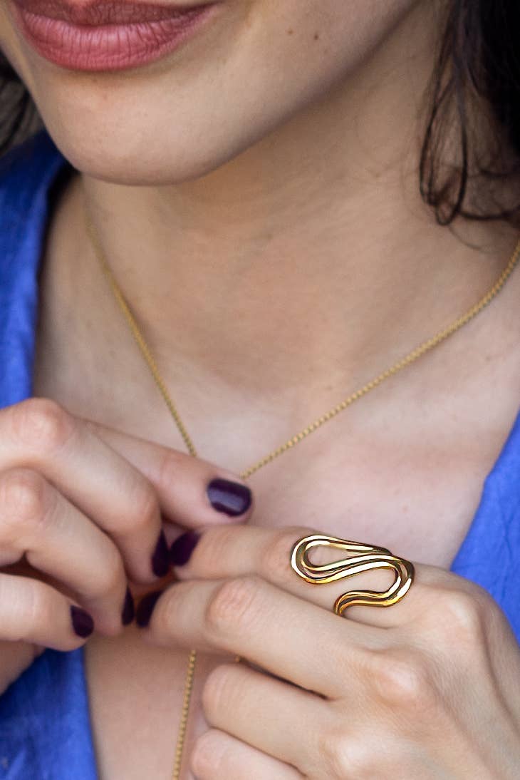 Close-up of a person wearing a gold wavy ring, with a blue garment partially visible.