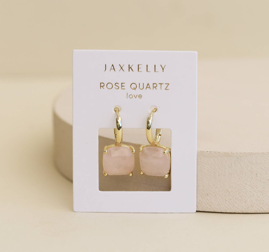 Jaxkelly rose quartz earrings on a display card against a beige background