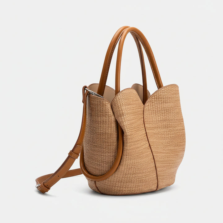 Brown woven raffia handbag with leather straps on a white background