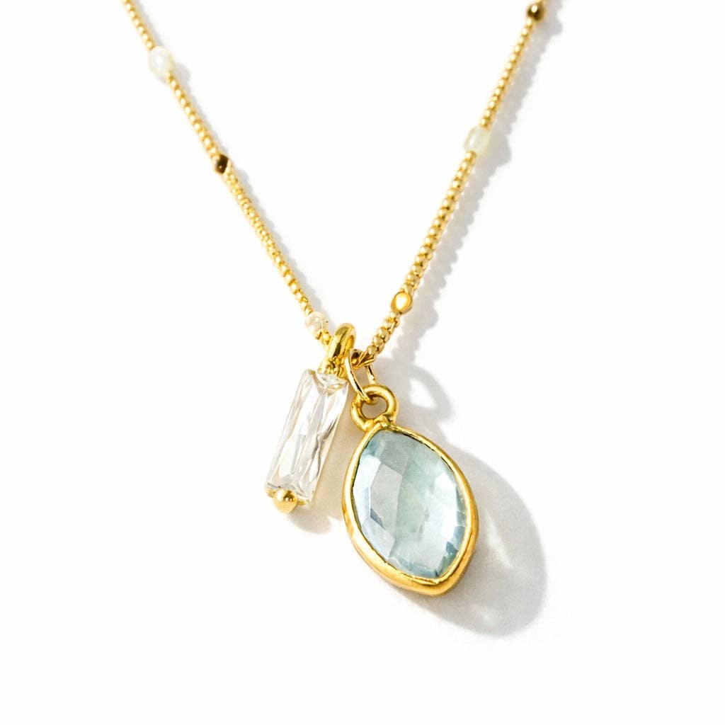 Gold necklace with a aquamarine teardrop pendant on a white background
