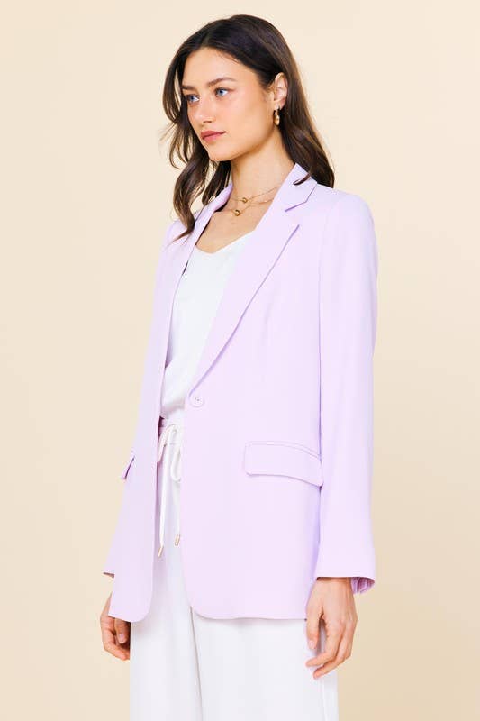 Woman wearing a light purple blazer over a white top on a beige background