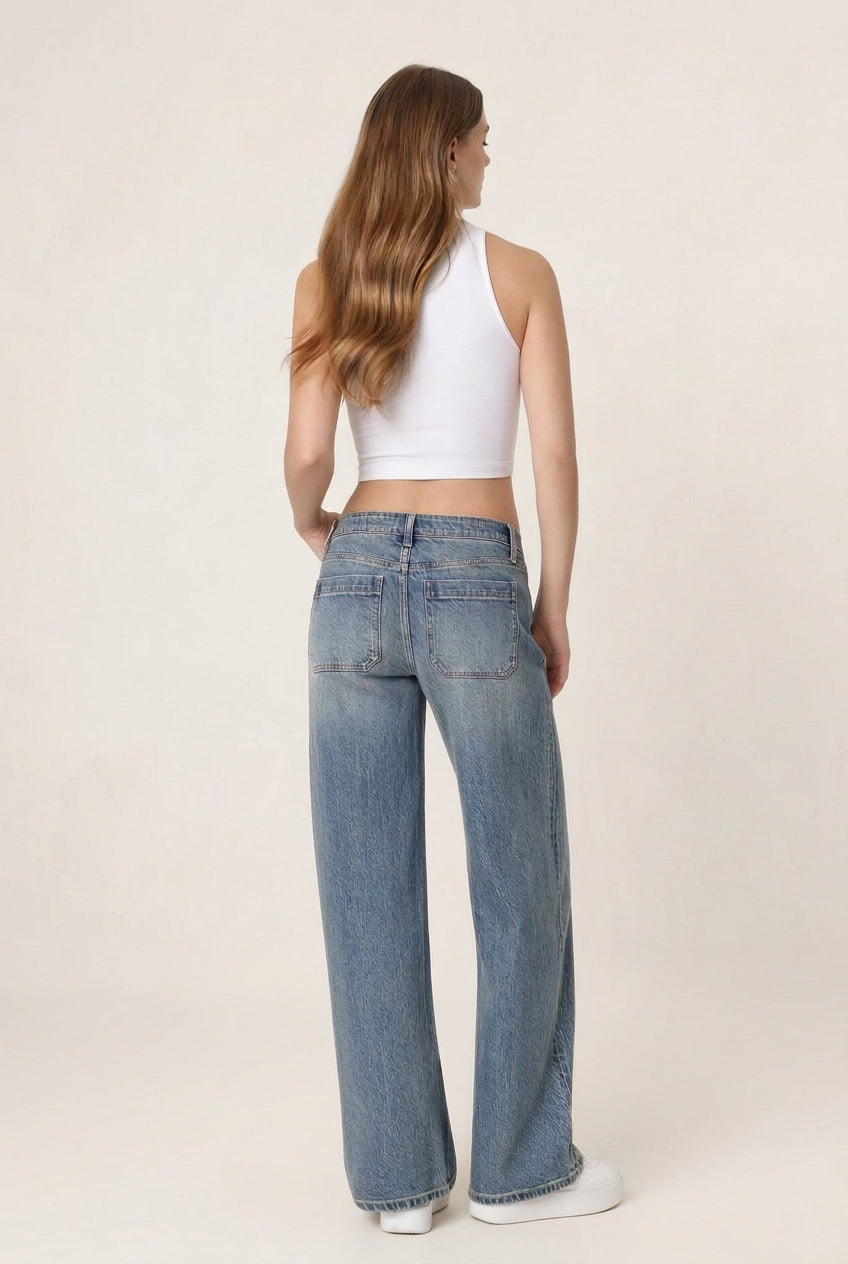 A woman shown from the back wearing light-wash blue wide-leg jeans and a white sleeveless crop top, standing against a plain white studio background.