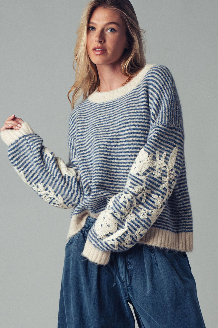 Woman wearing a blue and white striped sweater on a gray background