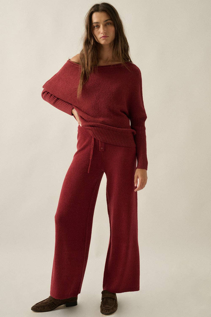 Woman wearing a burgundy sweater and sweater pants lounge set on a beige background