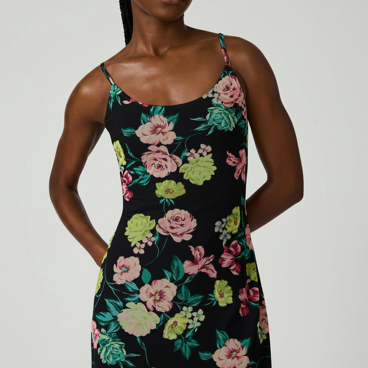 Woman wearing a black floral dress with pink and green flowers on a white background